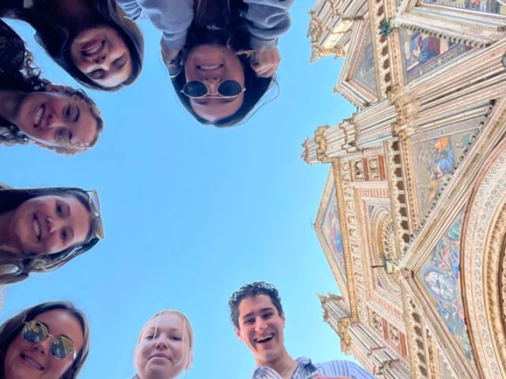 looking up at student faces, blue sky and an Italian cathedral facade