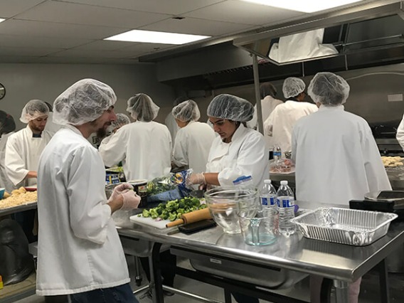 Students busy cooking at different kitchen stations