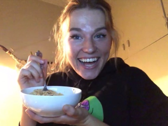 Online smiling student holding up bowl of pasta