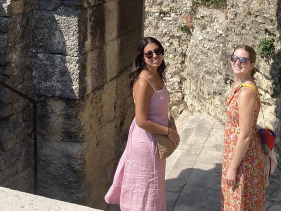 Two students smiling in sunglasses standing on stairs in Italian city