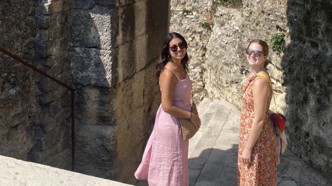 Two students smiling in sunglasses standing on stairs in Italian city